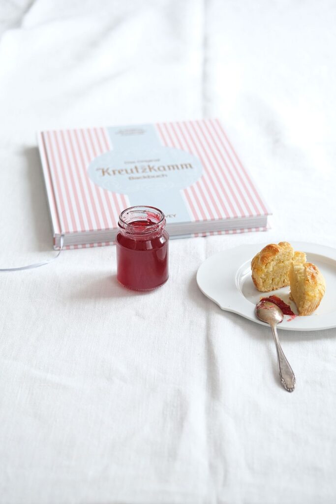 Brioche auf weißem Porzellanteller und ein Glas Himbeergelee